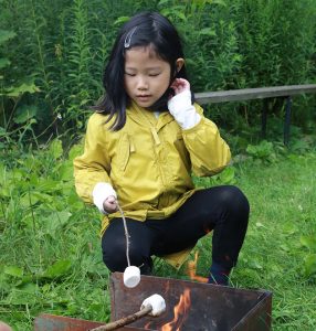 young girl roasts marshmallow over fire