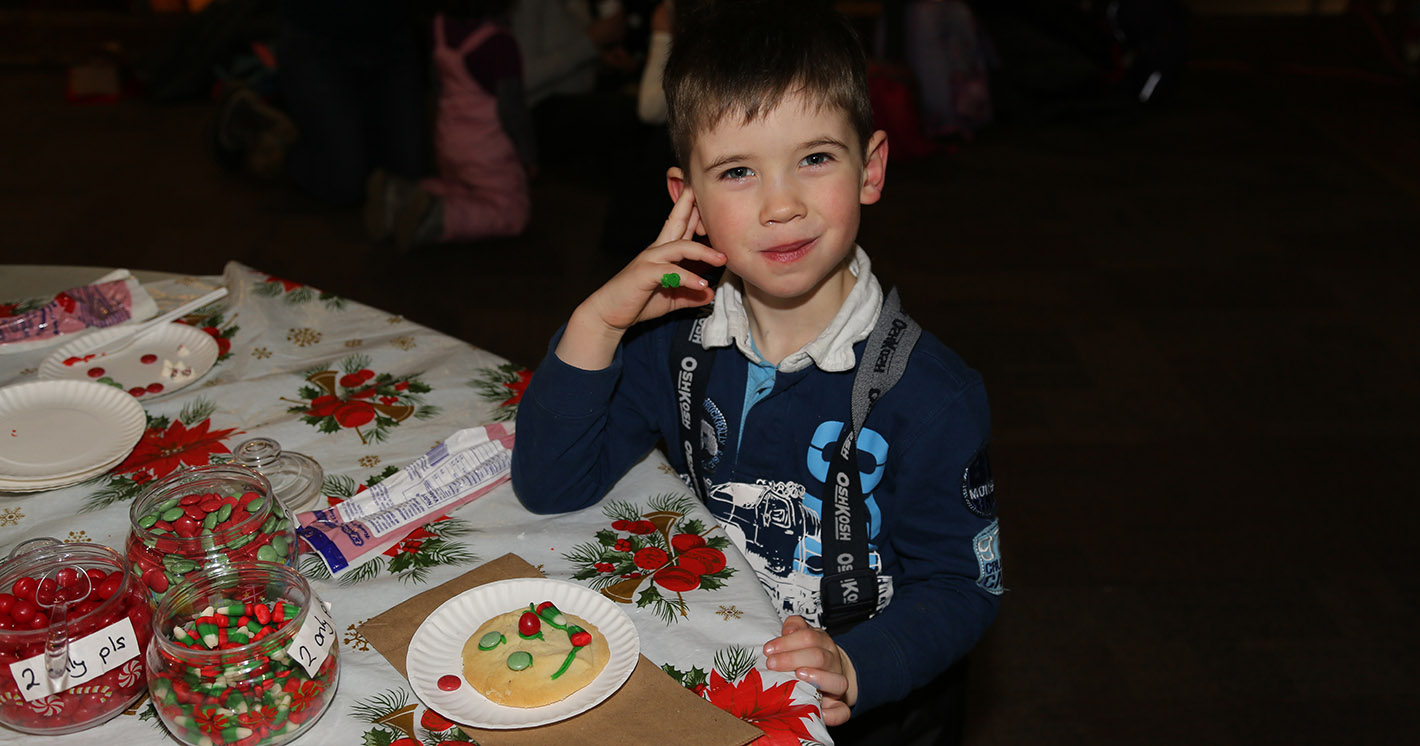 young boy decorates cookie at holiday party