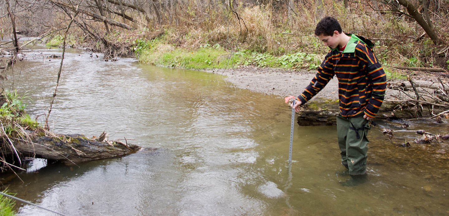 high school student takes stream flow measurement at Kortright Centre