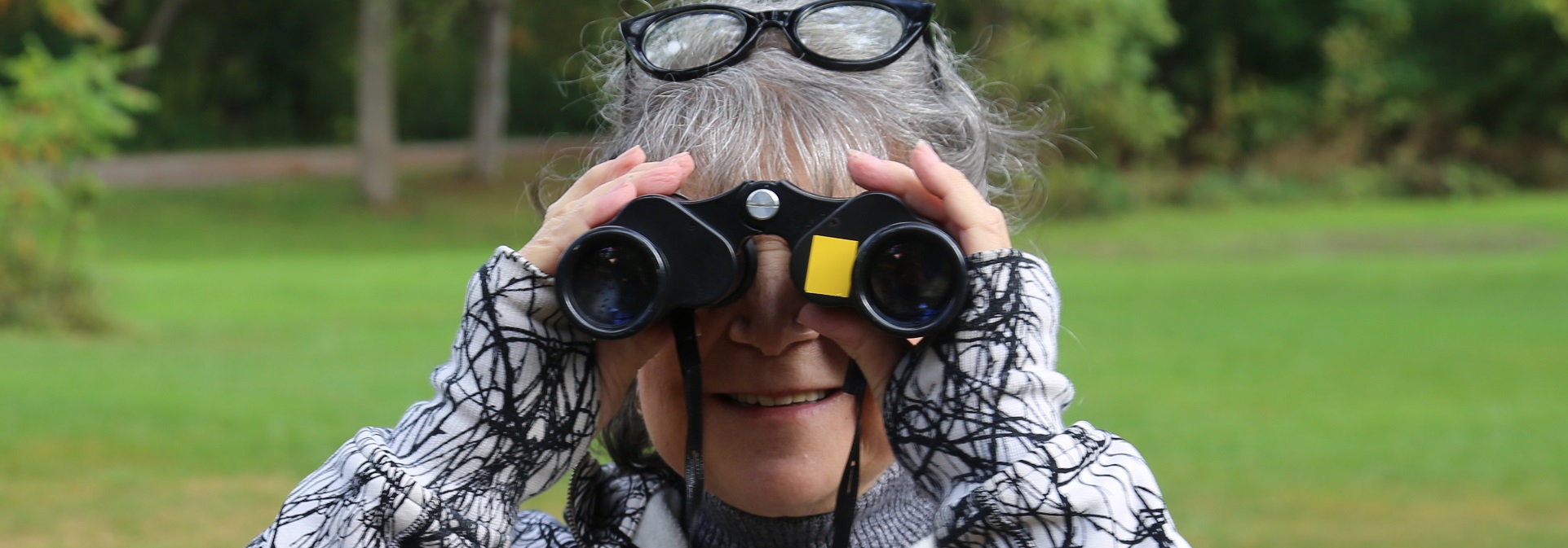woman uses binoculars to birdwatch