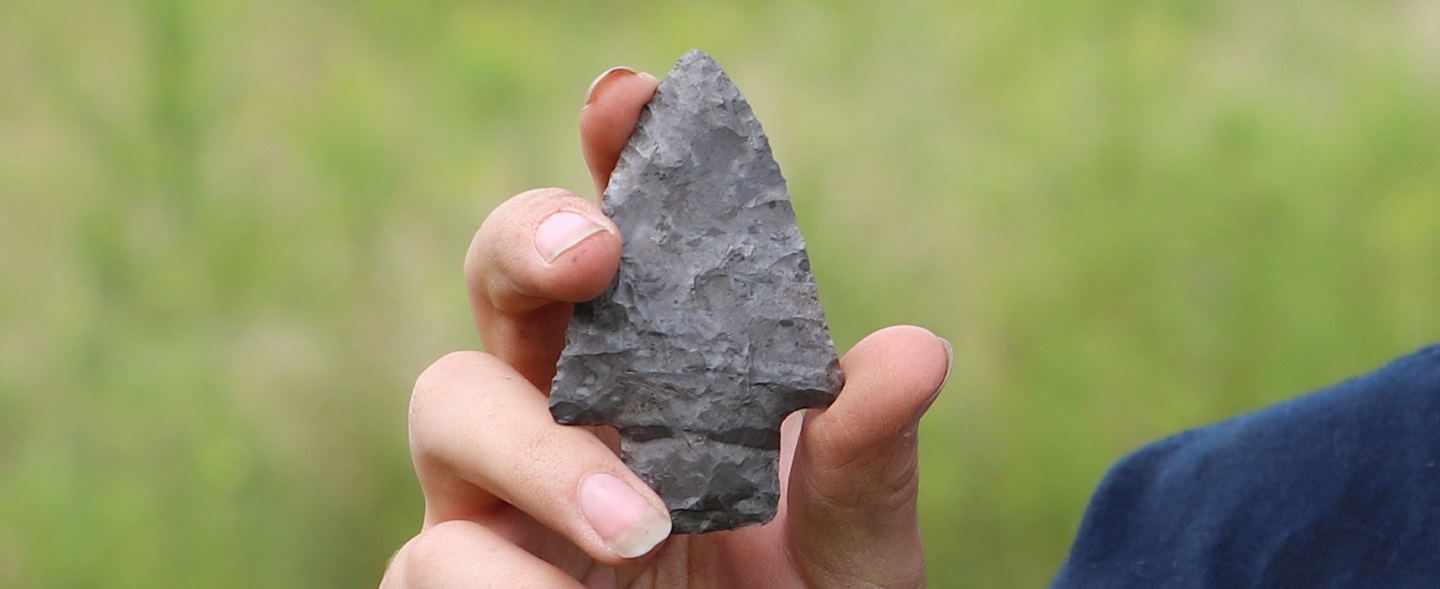 archaeology student holds arrowhead