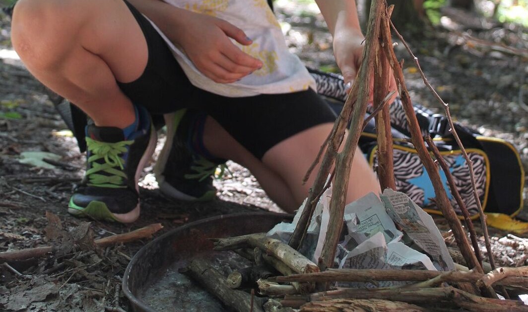 girl learns to build fire at Kortright summer survival skills day camp