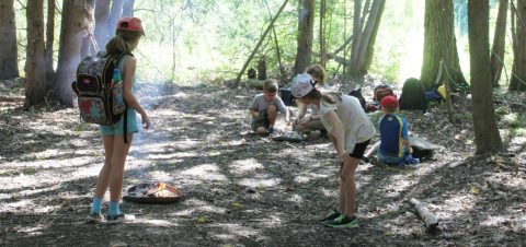 summer campers learn how to start a fire safely in wilderness survival program