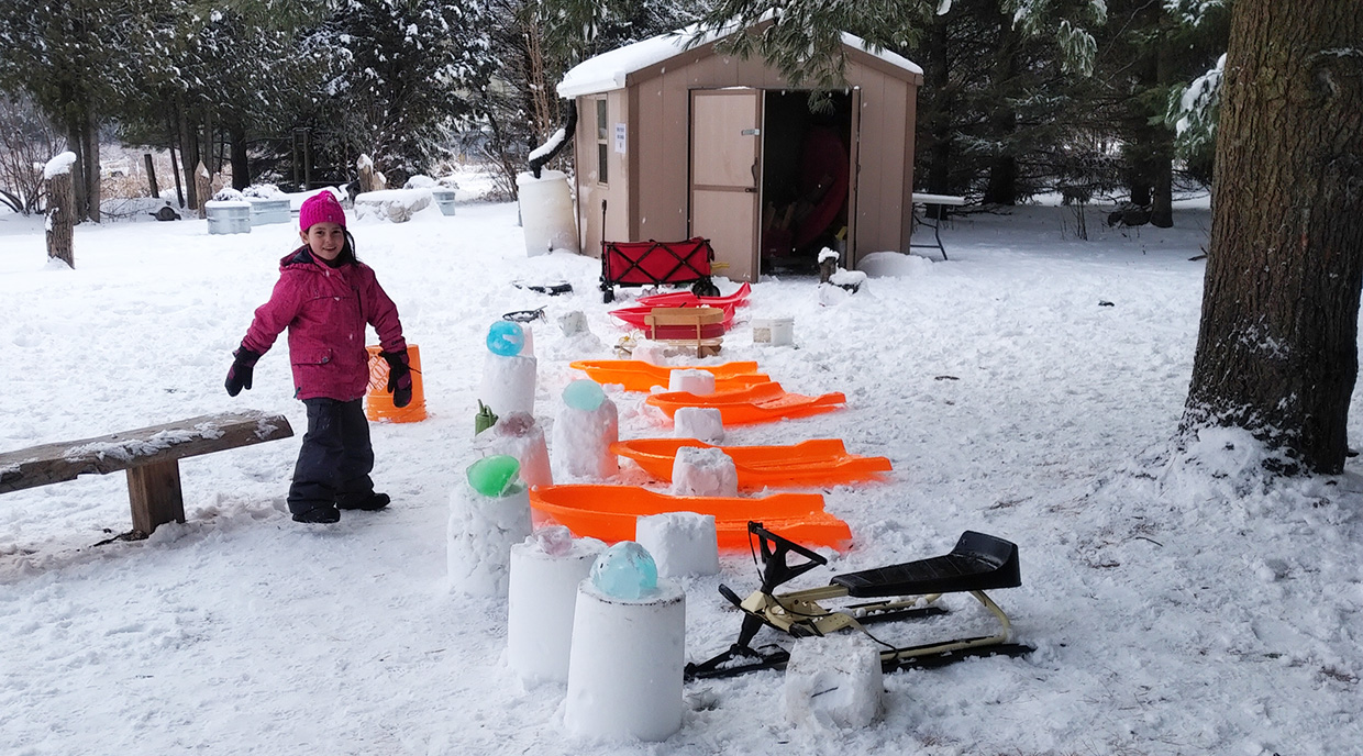 Nature School student proudly displays a parking garage for sleds built with ice and buckets