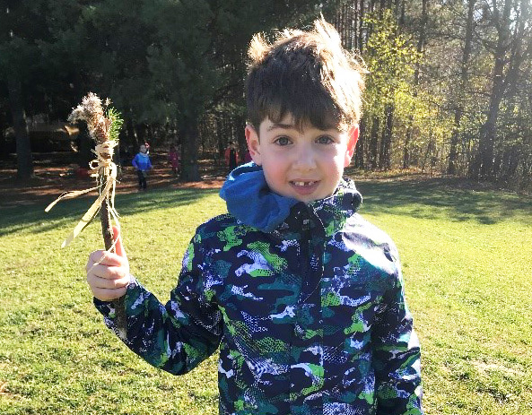 student at The Nature School at Kortright Centre proudly holds up a stick