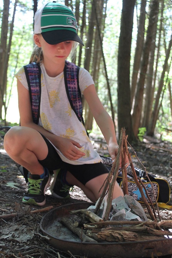 summer camper learns how to start a fire safely in wilderness survival program